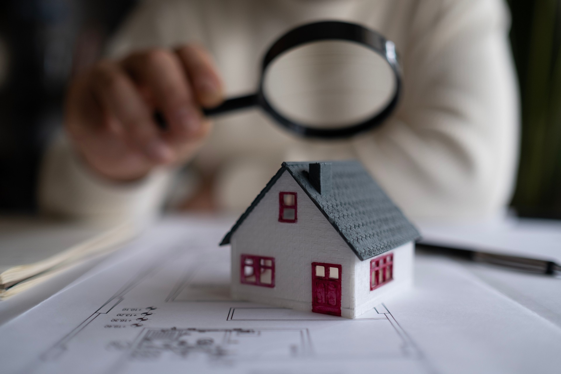 House model with man holding magnifying glass home inspection or searching for a house